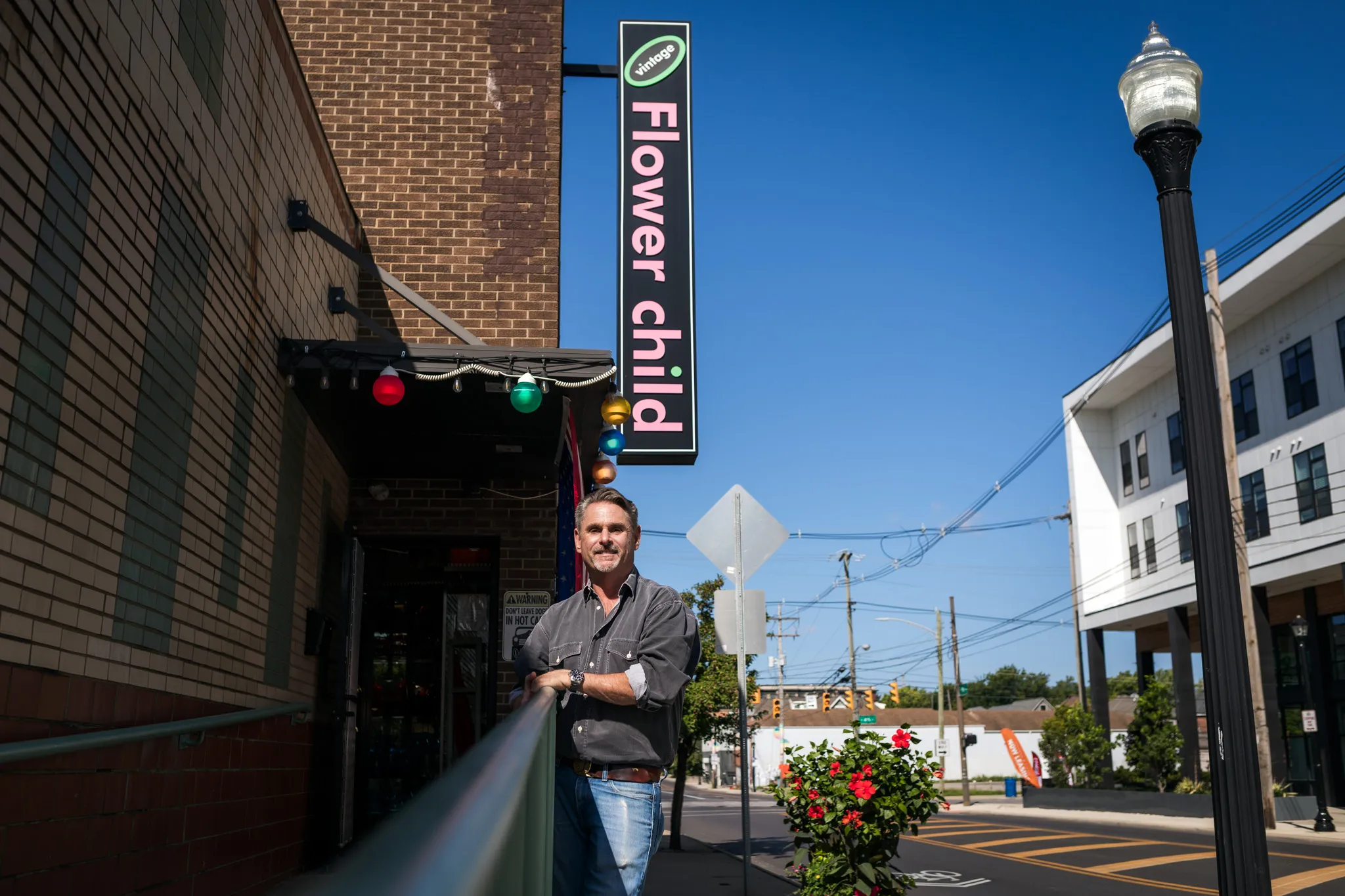 Man standing outside Flower Child restaurant sign.