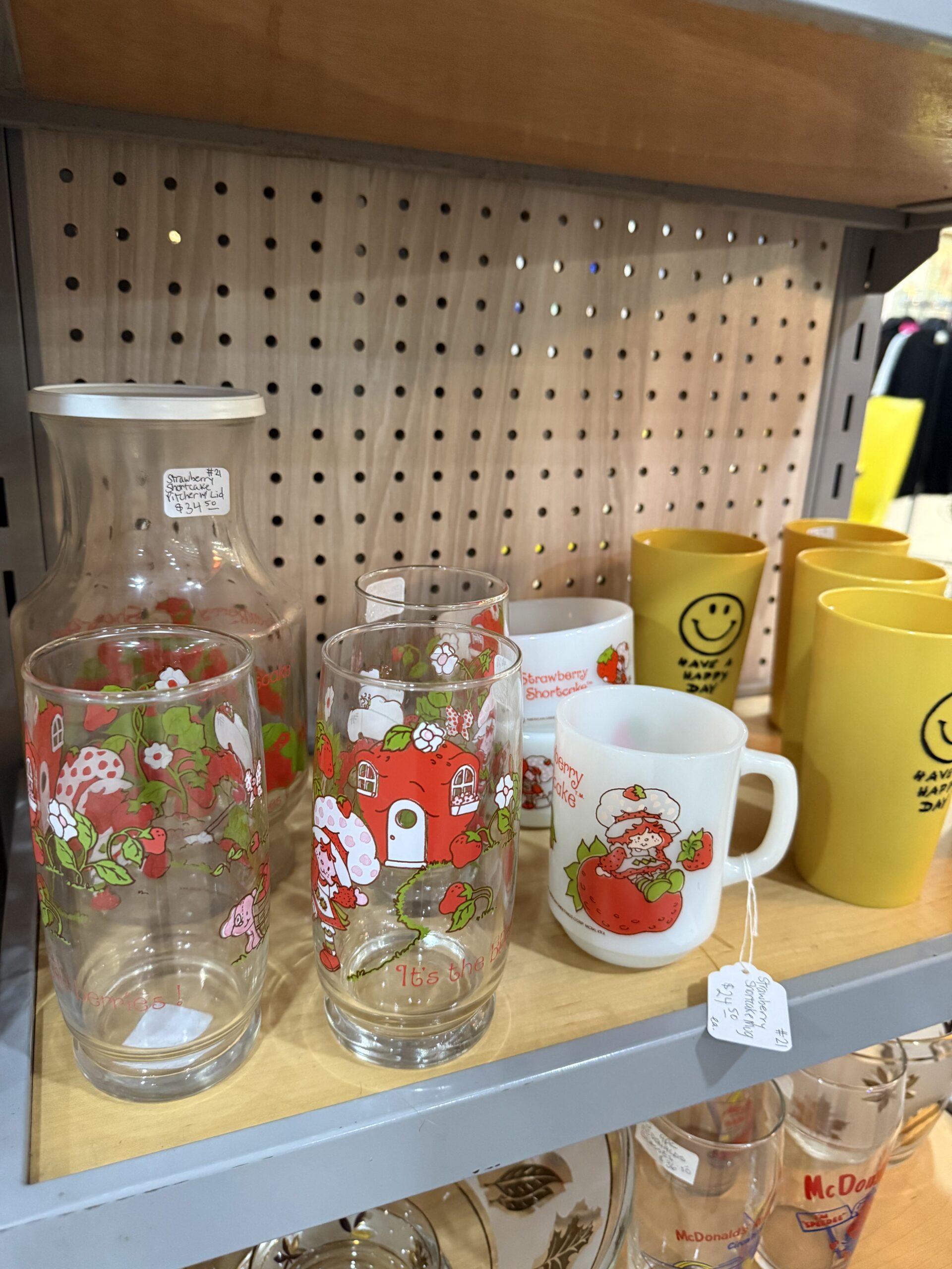 Vintage glassware and mugs on display shelf.